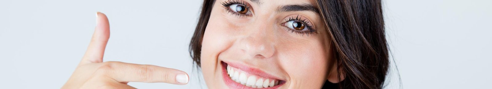 Happy woman pointing at her teeth after having dental filling treatment